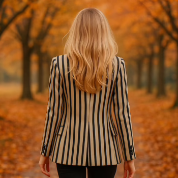 A blonde woman in a striped blazer and high boots walking away on an autumn path, symbolizing the journey of a first hotwife experience