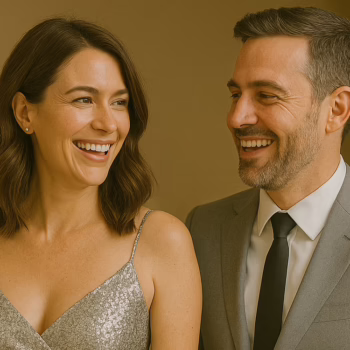 Smiling couple dressed in elegant cocktail outfits getting ready for a night out, the woman wearing a silver glitter dress and the man in a light gray suit – perfect example of what to wear in a swinger club.