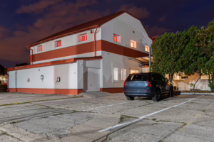 The modern two-story building of Labirintus Swinger Club Budapest lit up at night, showing the discreet parking area and industrial surroundings.