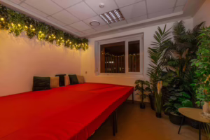 Cozy red-lit lockable playroom with low couches and ambient lighting on the ground floor of Labirintus Swinger Club Budapest.