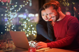 Smiling couple looking at a laptop together, showing healthy online swinger communication and shared connection.