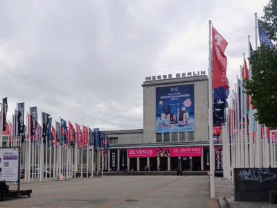 Exterior view of Messe Berlin with flags, banners, and advertising for the Venus Berlin Festival 2025