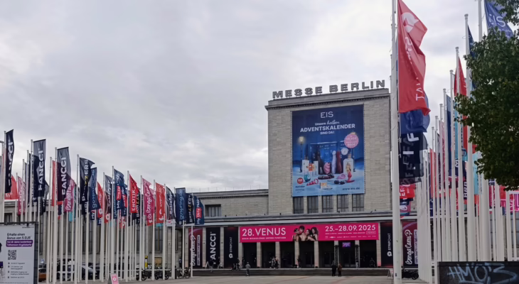Exterior view of Messe Berlin with flags, banners, and advertising for the Venus Berlin Festival 2025