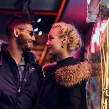 A nervous couple arriving together for their first swinger club experience, holding hands and smiling with anticipation.