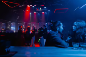 A stylish nightlife scene with couples dancing under colorful lights, capturing the playful and social energy behind doable hotwife dares for couples.