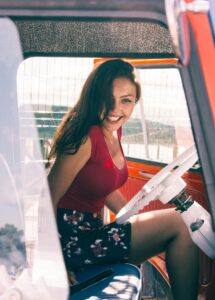 Confident woman smiling inside a vintage vehicle, symbolizing curiosity and personal confidence in modern swinger lifestyle exploration.