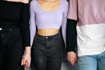 Three people holding hands representing ethical non-monogamy and polyamory relationship dynamics