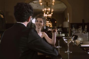 Man and woman talking at a bar with eye contact, showing a natural way to approach couples at a swinger club