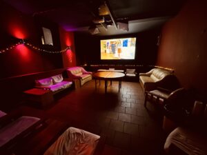Cinema-style lounge at Lovekino with sofas, screen, and ambient red lighting for relaxed socializing
