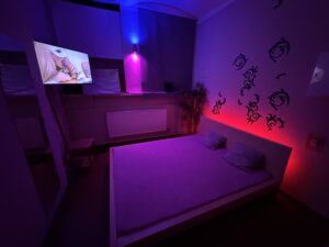 Private room at Lovekino with bed, soft lighting, and screen creating an intimate atmosphere