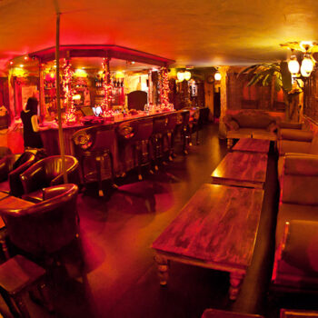 Lounge area at Moon City Paris with warm red lighting, statues, and intimate seating atmosphere