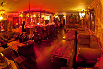 Lounge area at Moon City Paris with warm red lighting, statues, and intimate seating atmosphere