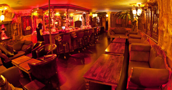Lounge area at Moon City Paris with warm red lighting, statues, and intimate seating atmosphere