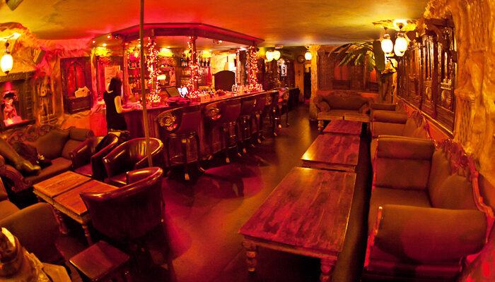 Lounge area at Moon City Paris with warm red lighting, statues, and intimate seating atmosphere
