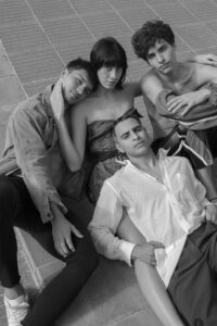 ENM vs. Poliamory: Group of young adults sitting closely together showing emotional intimacy and polyamorous connection