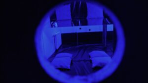 Private playroom at Tucan Club Denmark viewed through a circular opening with blue lighting and soft cushions