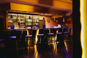 Bar at Swinger Club Paradiso with illuminated shelves and seating where guests gather and socialize
