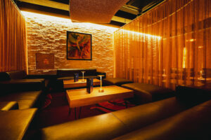 Lounge area at Swinger Club Paradiso with sofas, warm lighting, and semi-private seating behind curtains