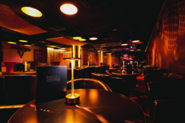 Social lounge at Swinger Club Paradiso with tables, ambient lighting, and relaxed atmosphere for conversation
