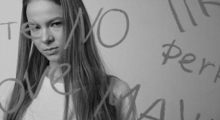 Woman looking serious through glass with words written on it, representing frustration from swinger dating mistakes and being ignored online