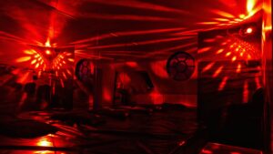 Red-lit playroom at Tucan Club Denmark with mirrors, soft bedding, and immersive lighting atmosphere