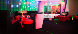 Social lounge and bar seating area inside ATLANTIS Rivesaltes with colorful ambient lighting