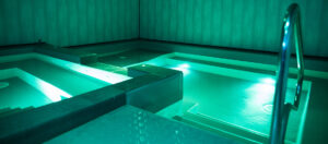Indoor pool and spa area at ATLANTIS Rivesaltes with ambient turquoise lighting