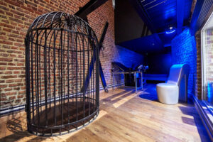 Fetish-themed playroom at Club Cocoon Brussels featuring a cage and BDSM furniture