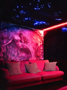 Cozy lounge corner inside Club Cocoon Brussels with mermaid wall art and sensual ambient lighting