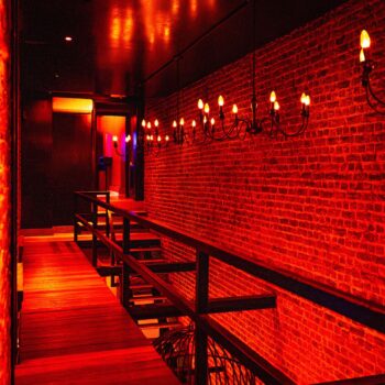 Red illuminated hallway inside Club Cocoon Brussels swinger club with exposed brick walls and elegant lighting