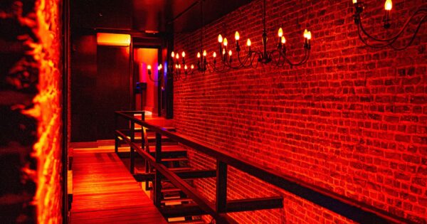 Red illuminated hallway inside Club Cocoon Brussels swinger club with exposed brick walls and elegant lighting