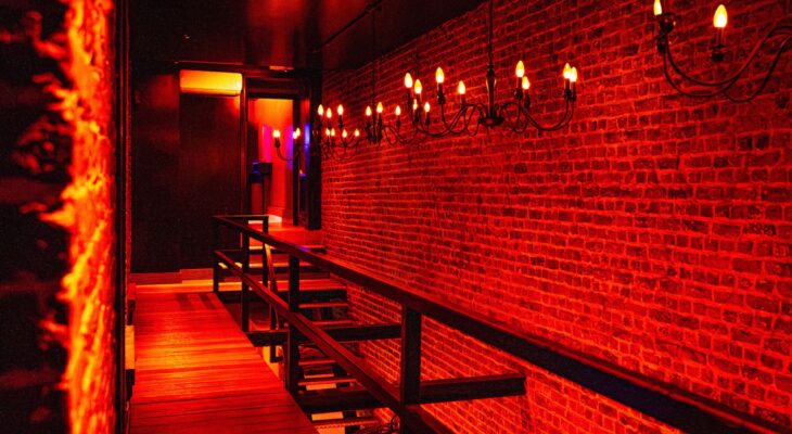 Red illuminated hallway inside Club Cocoon Brussels swinger club with exposed brick walls and elegant lighting