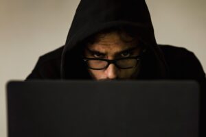 Anonymous person using a laptop to represent a catfish or scammer creating fake swinger profiles on dating websites.