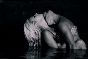 A couple shares a passionate embrace in the water, illustrating the chemistry, excitement, and emotional intensity of exploring the swinger lifestyle together.