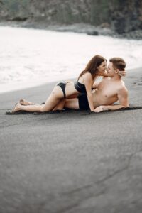 Couple sharing an intimate moment on a sunny beach, illustrating how vacation libido, relaxation, and holiday chemistry can strengthen attraction and desire.