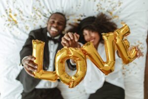 Happy couple holding gold LOVE balloons while celebrating their relationship